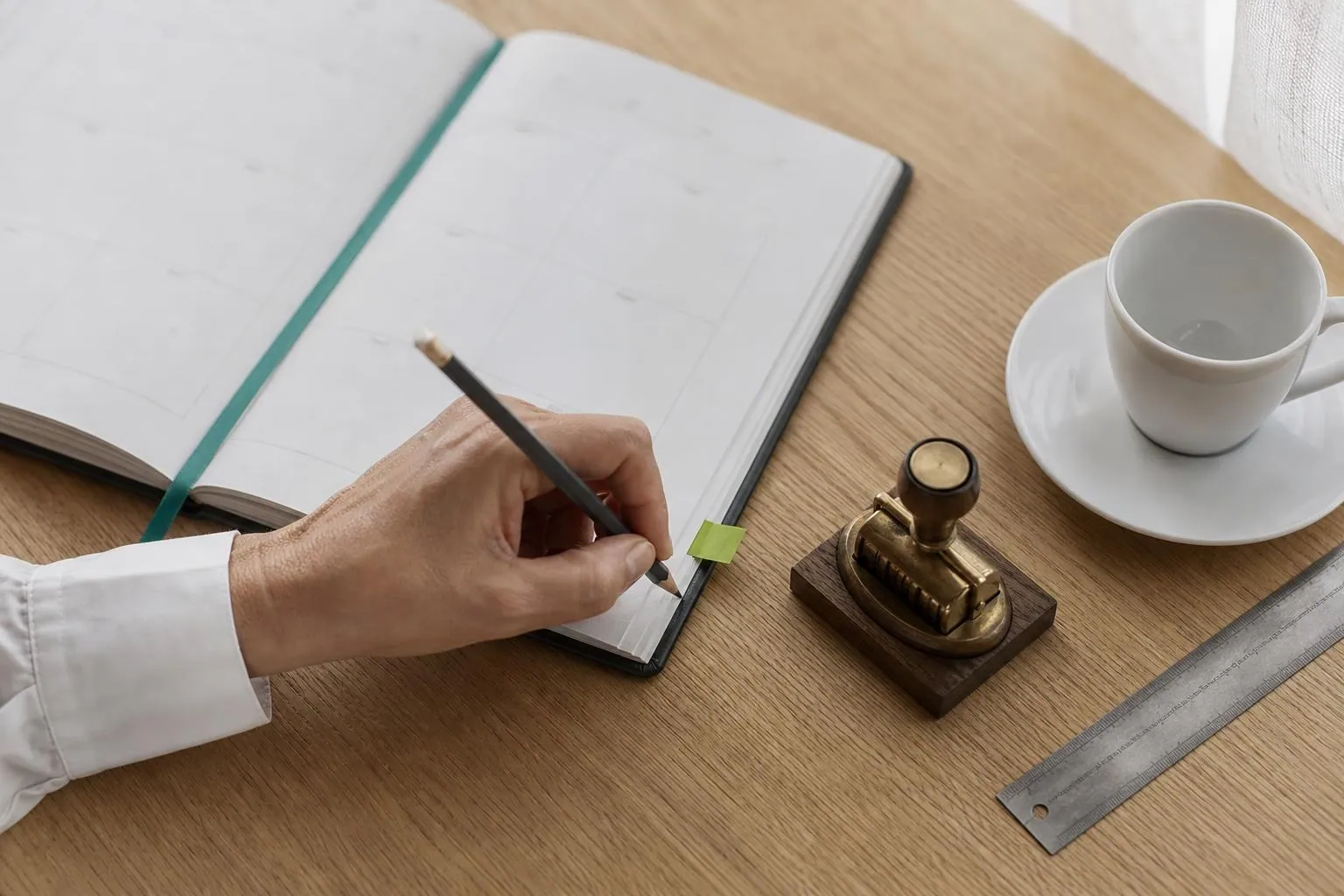 Main d une professionnelle annotant au crayon un agenda de bureau ouvert a cote d un tampon dateur